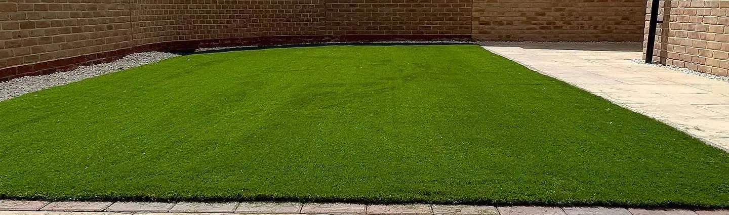Close view of an artificial lawn installed against a brick wall