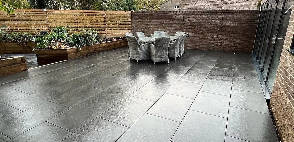 Dark porcelain patio with outdoor dining set and raised beds in Cambridgeshire