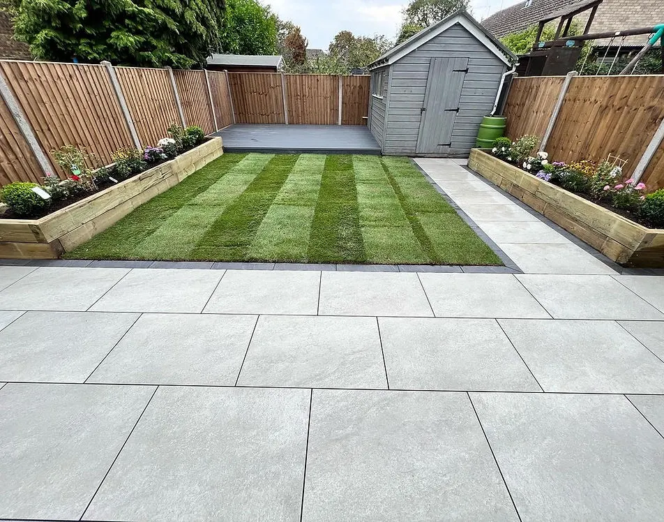 Completed garden transformation with striped lawn, sleeper beds and porcelain patio by JDS Landscaping