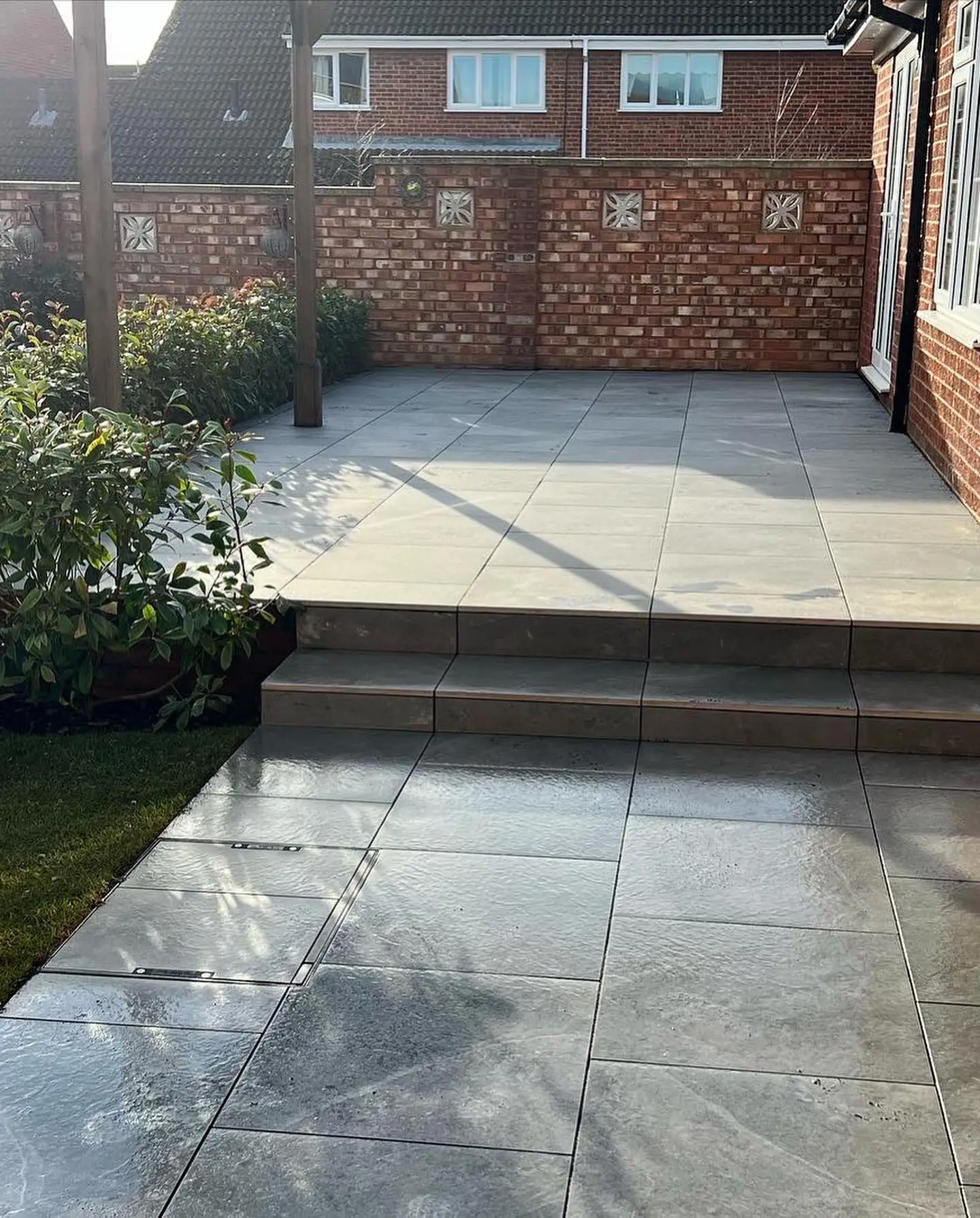 Porcelain patio with wide steps down to the lawn by JDS Landscaping